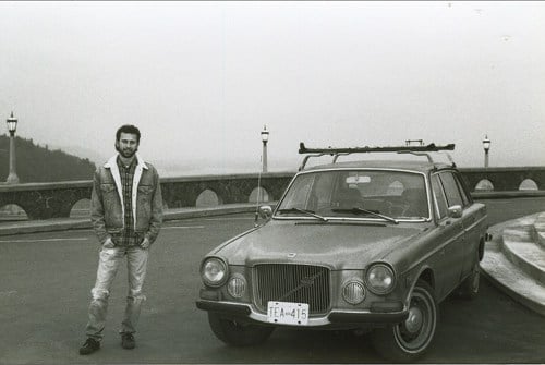 Vintage man with older Volvo car on bridge.