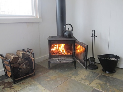Roaring wood burning fireplace with wood pile. 