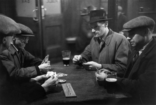 Vintage men playing cribbage in bar with beer wearing flat caps. 