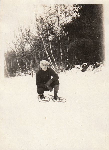 Vintage man in snowshoes kneeling in snow. 