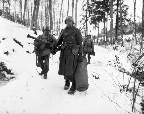 WWII soldiers christmas 1944 walking snowy ground forest. 