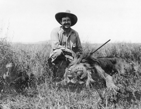 Young Ernest Hemingway smiling with dead lion gun in hand. 