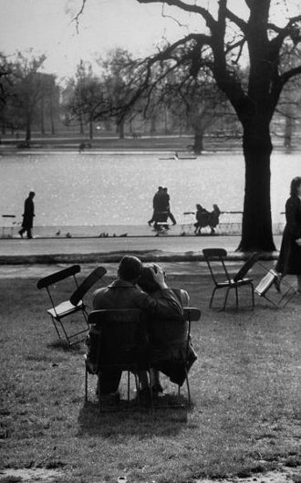 Vintage couple hugging on park bench near lake somber.