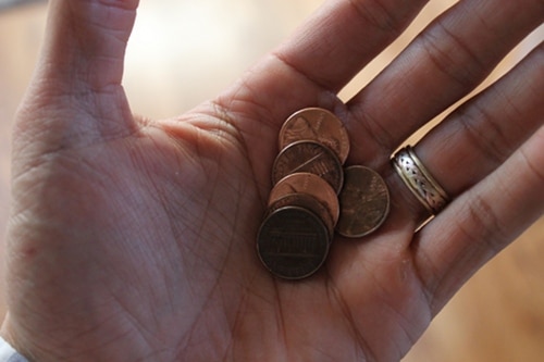 variety of pennies in man's hand