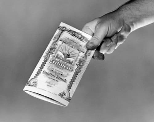 Vintage stock certificate of capital stock in man's hand. 