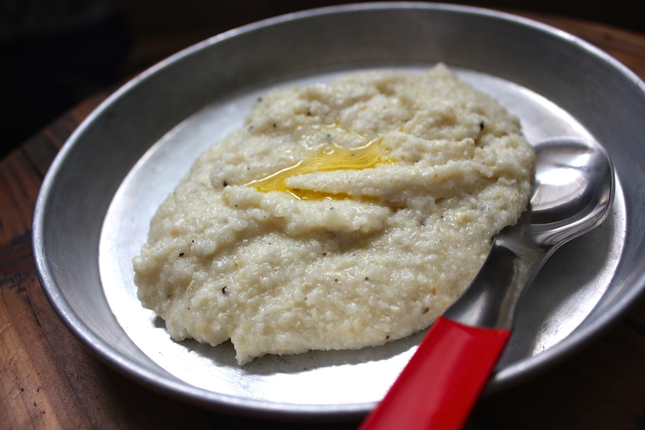 Cooked grits on aluminum plate with butter oil.