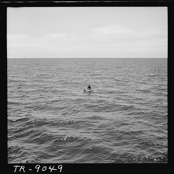 Vintage man in a life raft in middle of ocean.