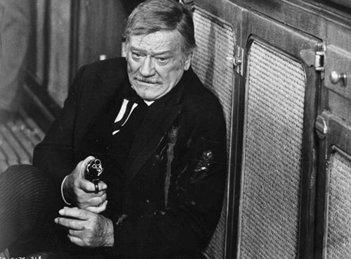 Shootist old western movie film john wayne on ground with gun.