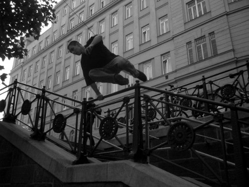 Hombre saltando por encima de la barandilla de la escalera foto blanca negra parkour.