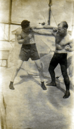 Vintage boxers fighting in ring taking punch.