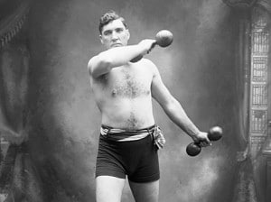 Vintage strongman posing working out with dumbbells.