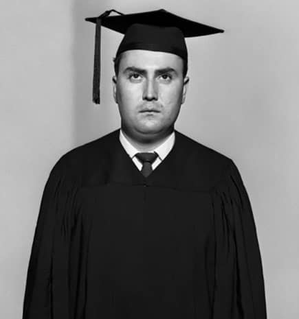 Vintage man in graduation robe and hat looking despondent.