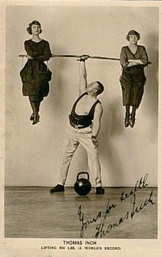 Vintage strongman thomas inch holding up two women.