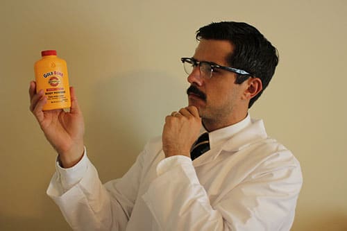 man in lab coat holding looking at gold bond 