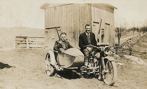 Vintage men on motorcycle with side car.