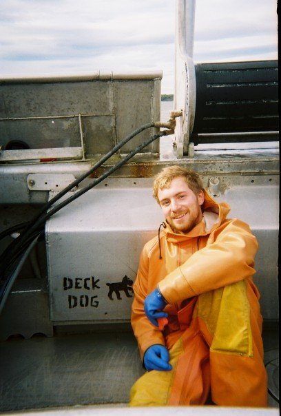 Commercial fisherman on boat in orange rubber suit.