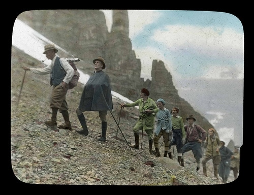 Vintage hiking expedition on mountain men women hiking poles.