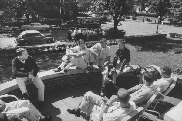 Vintage college students sitting outside talking shooting the breeze.