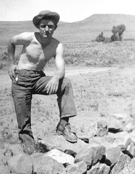 Vintage man leg on rock posing in desert shirt off.