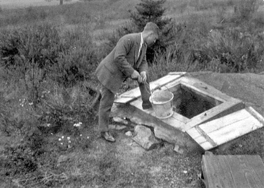 Vintage man in suit looking down into well hole.