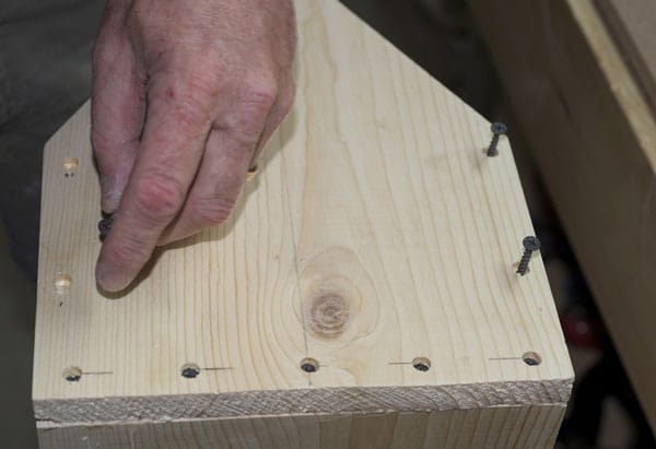 Man drilling and countersink a few holes on the end pieces.