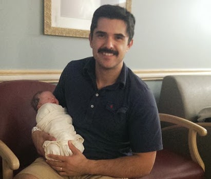 Man dad with newborn baby girl swaddled.