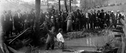 Vintage man being baptized in outdoor pond african american black church.