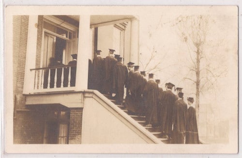 Graduation group men in robes walking up stairs.