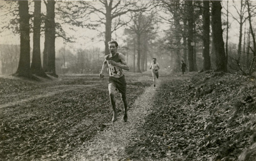 Vintage man trail running through forest woods.