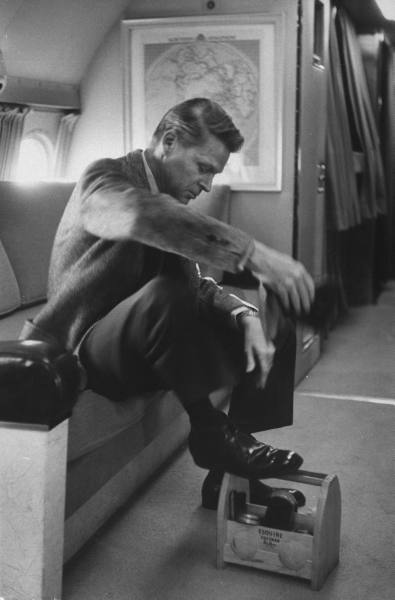 Vintage man on airplane shining shoes on shoe shine box.