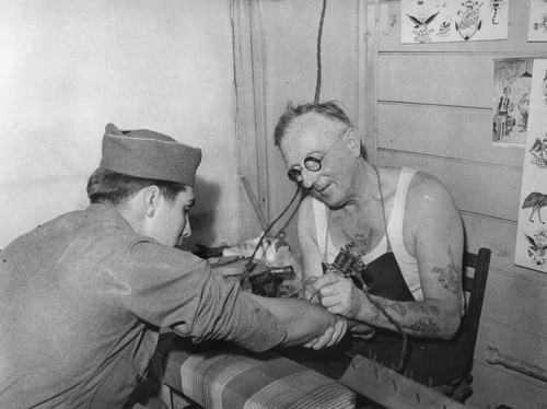 Vintage soldier military man getting tattoo on forearm.