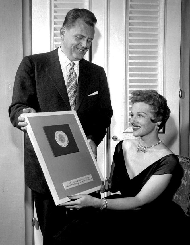 Vintage woman receiving award plaque smiling.