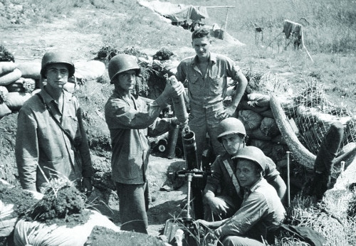 Vintage soldiers in trench loading grenade gun with bomb.