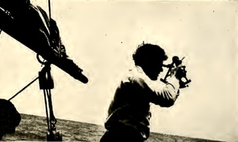 Jack London on sail boat looking out over sea water.