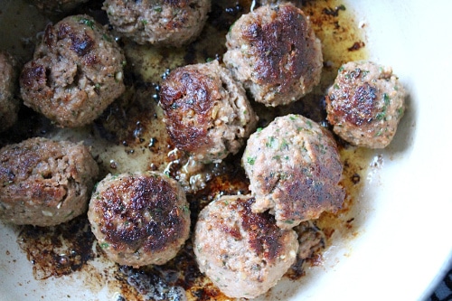 Cooked browned meatballs in ceramic dish.