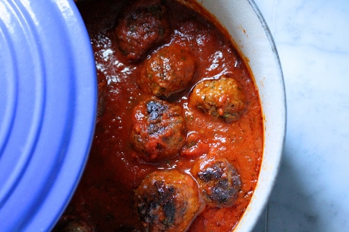 Cooked meatballs in red sauce ceramic le cruised dish.