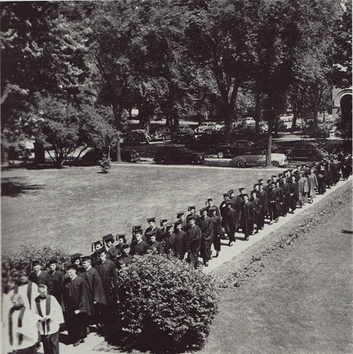 Vintage college group of graduates walking in robes.