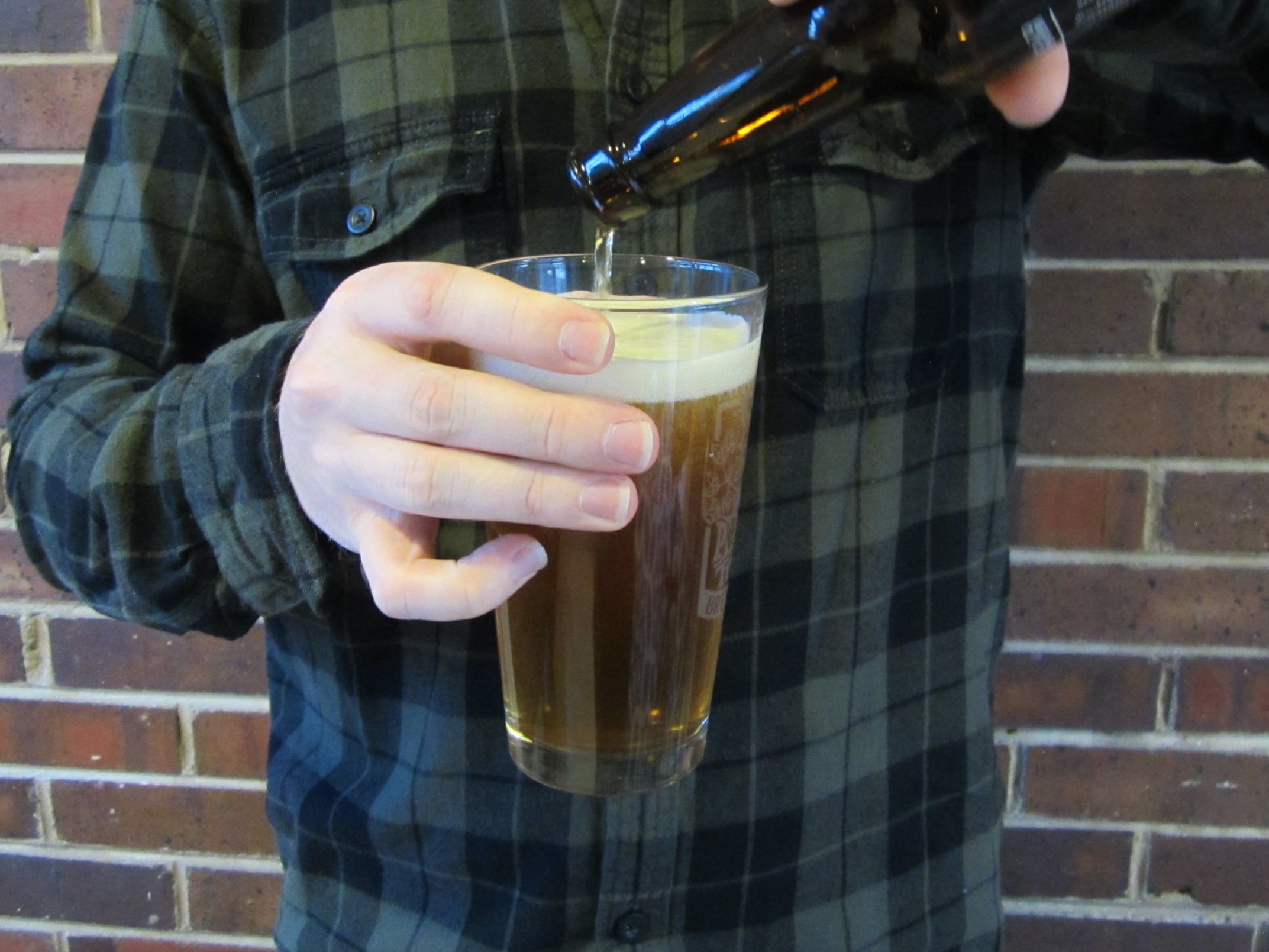 Man pouring beer into pint glass.