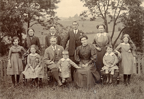 Vintage family with a lot of kids sitting for portrait.