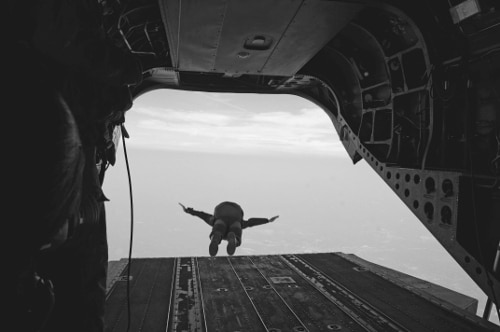Vintage soldier paratrooper jumping out of back of airplane.