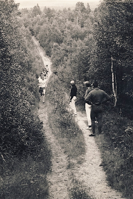 Vintage runners trail running through forest.