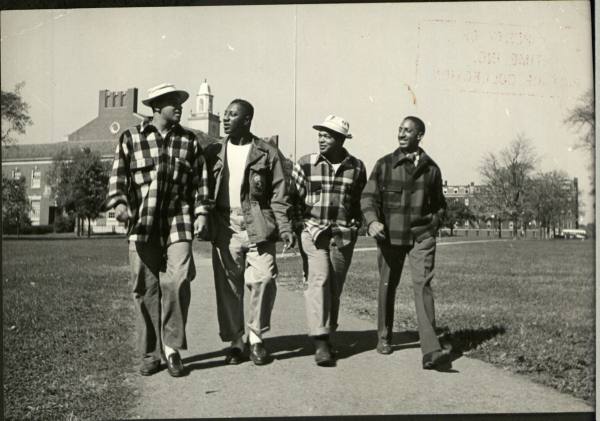 Four Vintage college African & American black friends talking each other on campus.