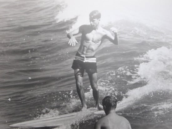 Vintage man on surfboard in ocean riding wave.