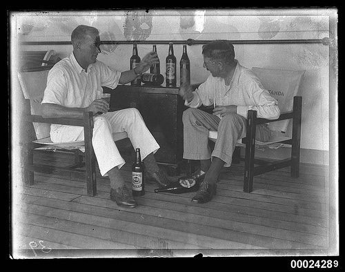 Vintage men sitting in chairs talking with beer bottles.