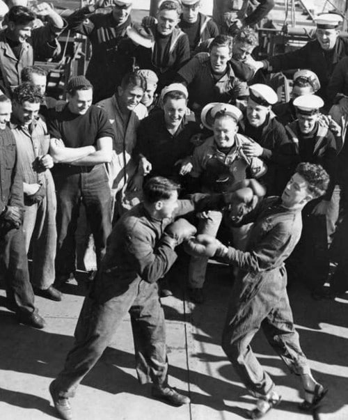 vintage amateur men boxing in street clothes with large group of onlookers