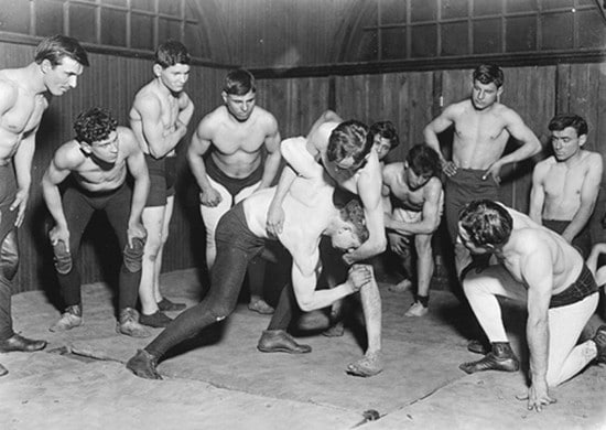 Vintage men wrestling in gym.