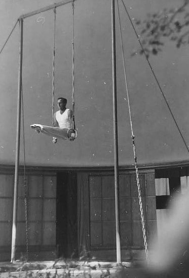 Vintage gymnast hanging on gymnastic rings.