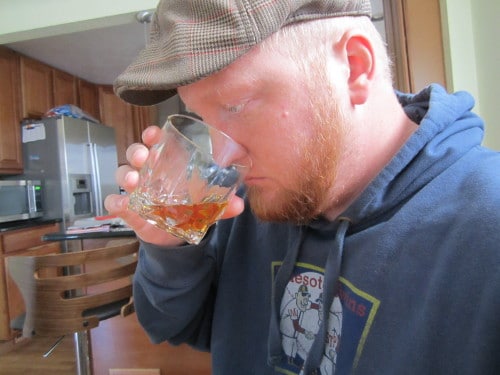 man sniffing whiskey in old fashioned rocks glass