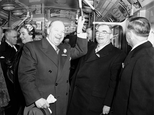 Vintage men in suits riding subway talking laughing.