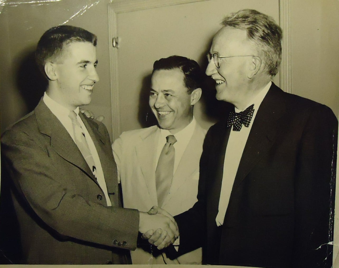 Vintage young man shaking hands with older businessman.